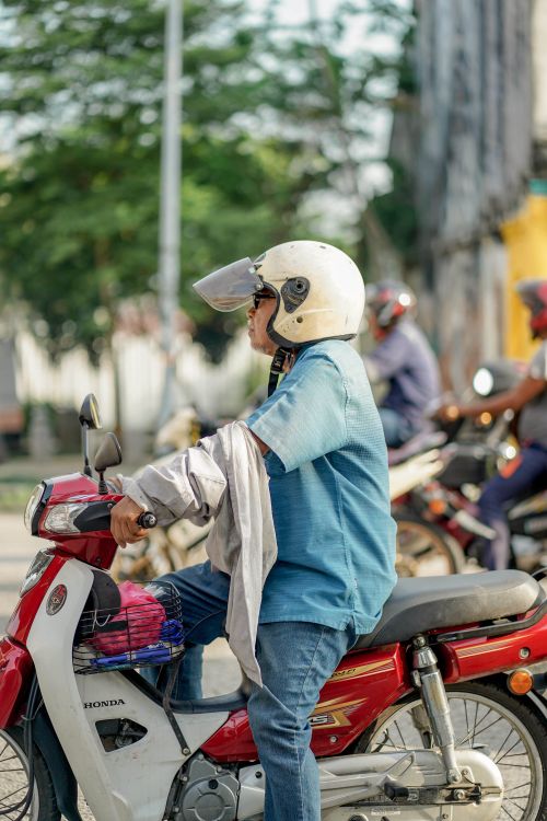 Free Man sitting on a motor scooter in Klang, Selangor, Malaysia, wearing a helmet. Stock Photo