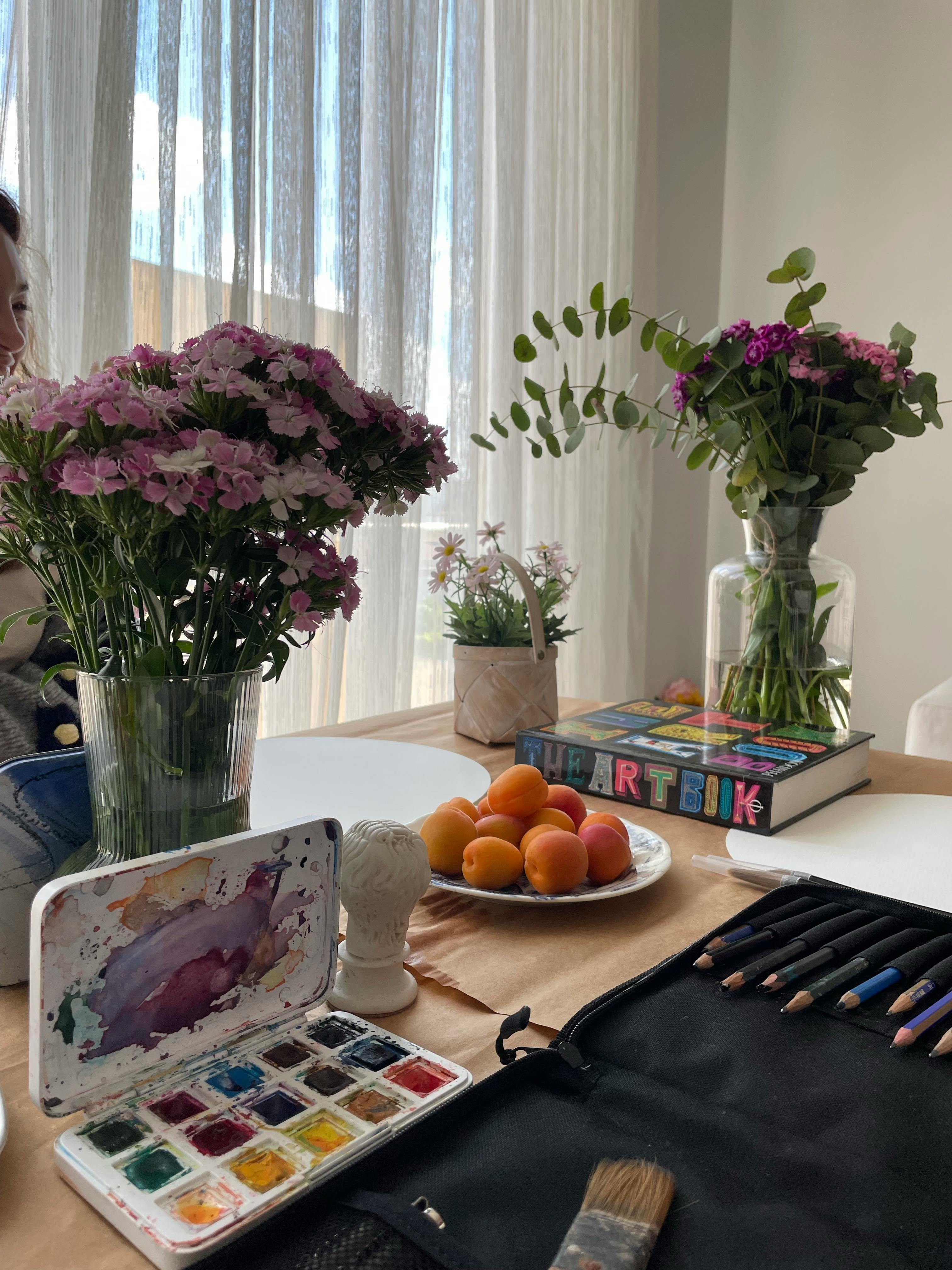 Art supplies with flowers and fruits in an İstanbul home, perfect for creative inspiration.
