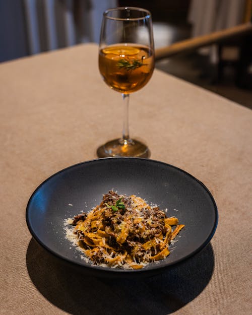 A plate of pasta with meat and a glass of wine