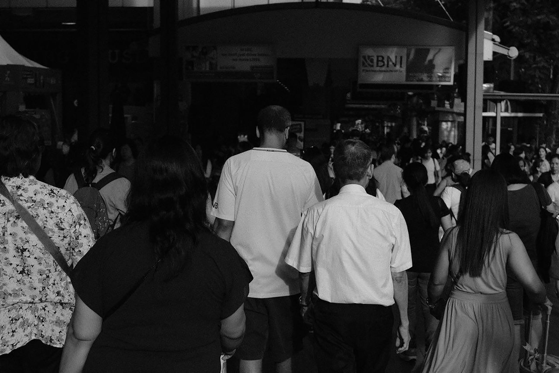Black and white back view of anonymous people waiting for train in crowded railway station