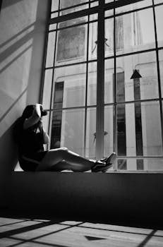 一个女人在大窗户旁拍下黑白剪影照