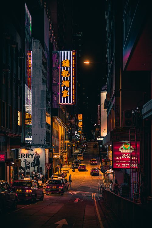 Free Experience the bustling nightlife of Hong Kong's urban streets with vivid neon signs and taxis. Stock Photo