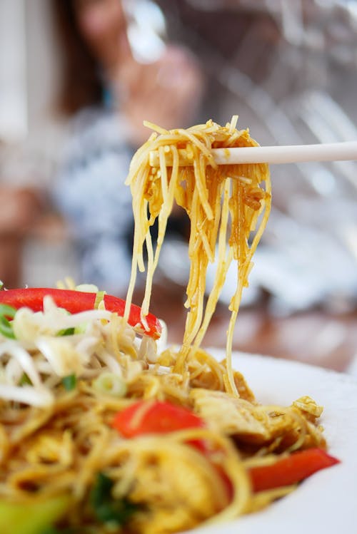 Person Picking Cooked Noodles with Chopsticks