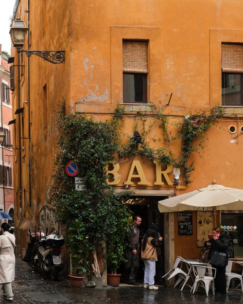 Free Rustic Italian bar with ivy-covered walls on a bustling street, perfect for urban explorations. Stock Photo