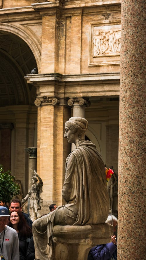 A statue of a woman sitting on a bench in front of a building