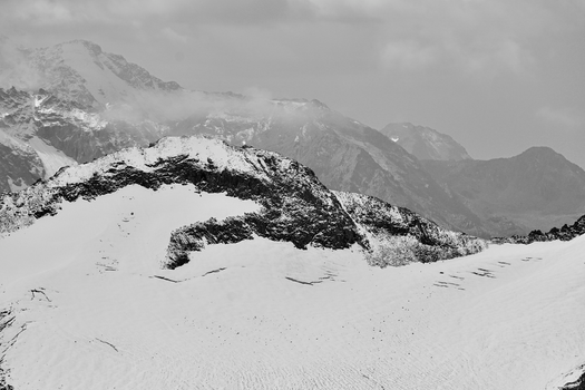 Black and white snowcapped mountain range with cloudy sky, perfect for travel or nature themes.