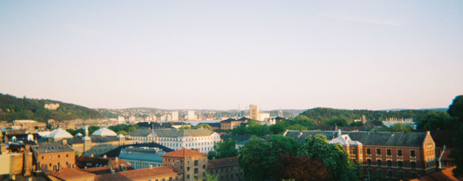 Captivating aerial view of Oslo with buildings and greenery under a clear sky.
