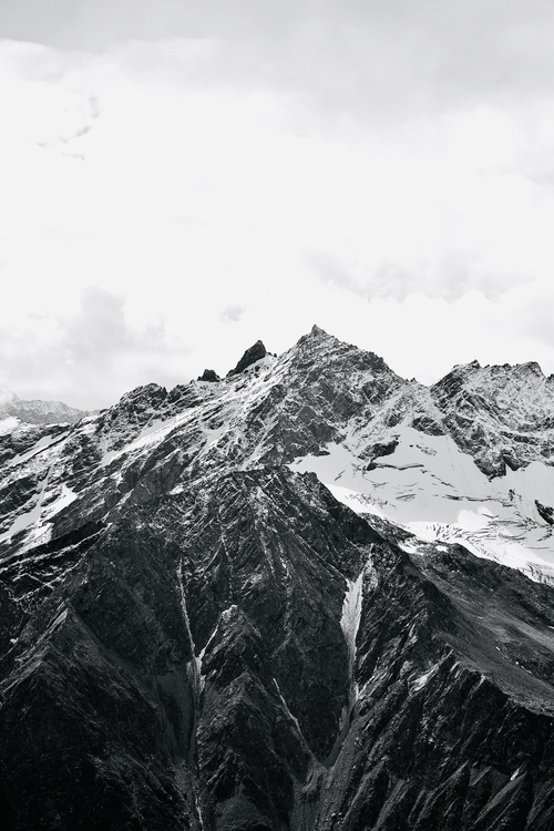 Free Breathtaking black and white photo of a snowcapped mountain range under a cloudy sky, ideal for travel and nature themes. Stock Photo