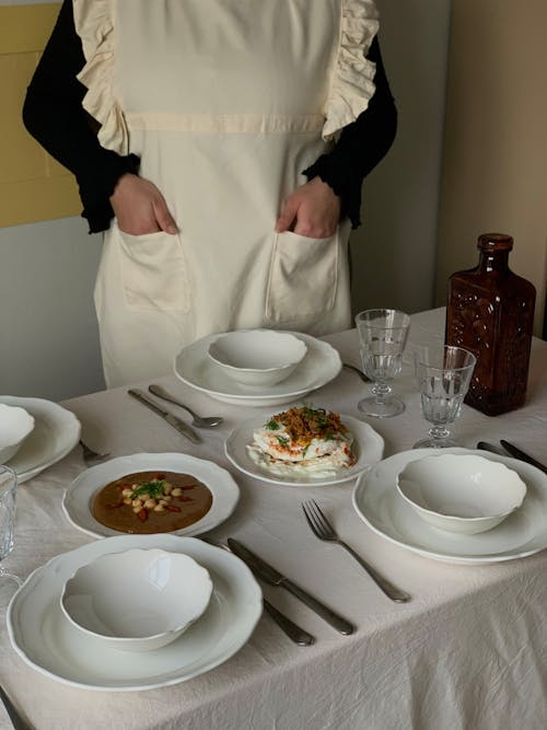 Free Woman in an Apron Standing behind a Set Table  Stock Photo