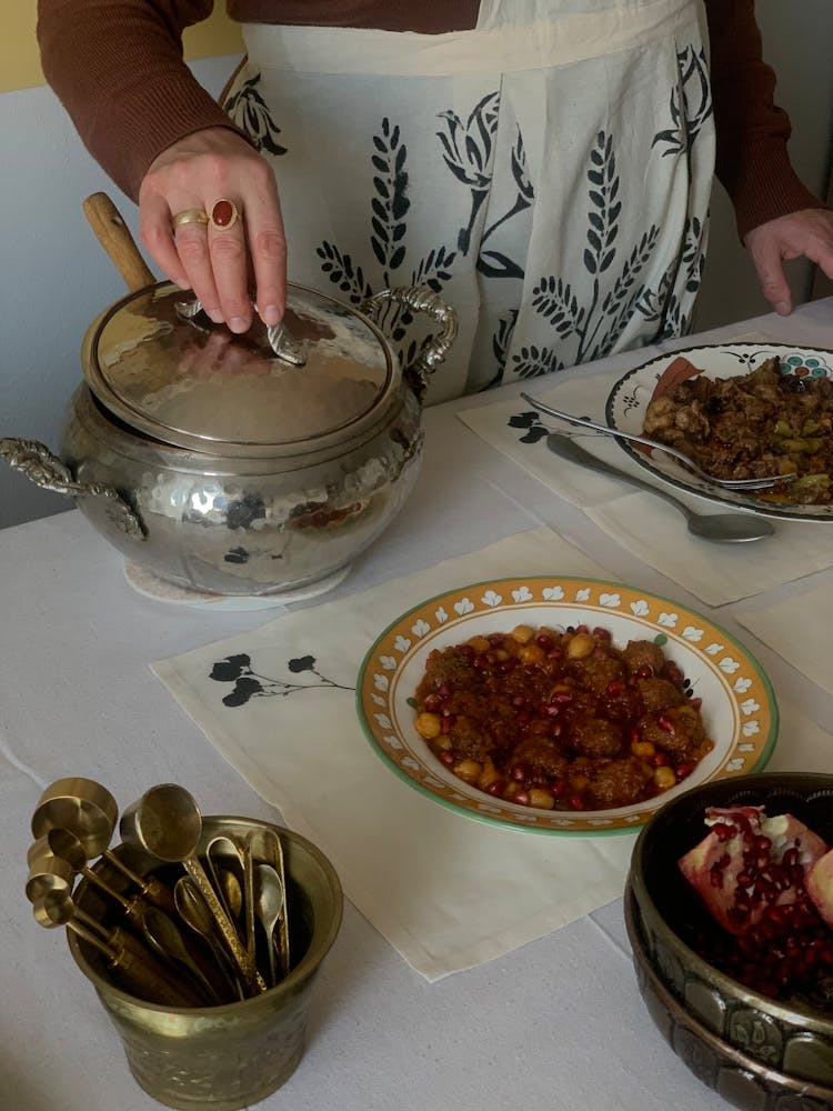 A Woman In An Apron Standing At A Set Table 