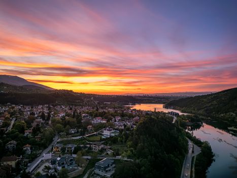 A breathtaking aerial view of Pancharevo, Sofia, Bulgaria, at sunset with vibrant colors over the hills and lake.