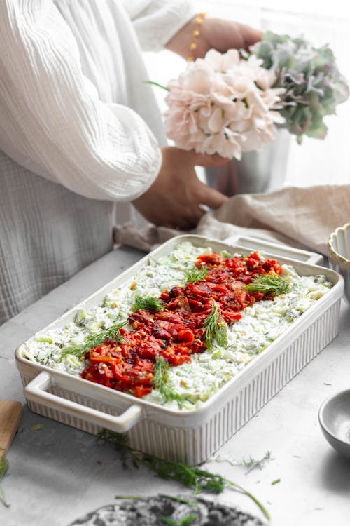 A woman is preparing a dish with vegetables