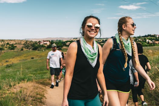 一群成年人戴着太阳镜和头巾，在阳光明媚的日子里徒步穿越草地