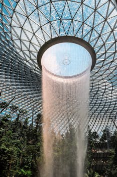 Stunning indoor waterfall at Jewel Changi Airport, Singapore, showcasing modern architecture and lush greenery.
