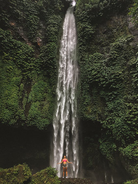 Woman Standing In Front Of Waterfalls