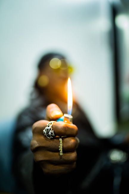 Close-up shot of a man holding a lighter with a burning flame, emphasizing selective focus.