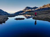 新西兰塔斯曼一个平静的湖边，一个男人的身影映衬着山峦的倒影，构成一幅宁静的场景
