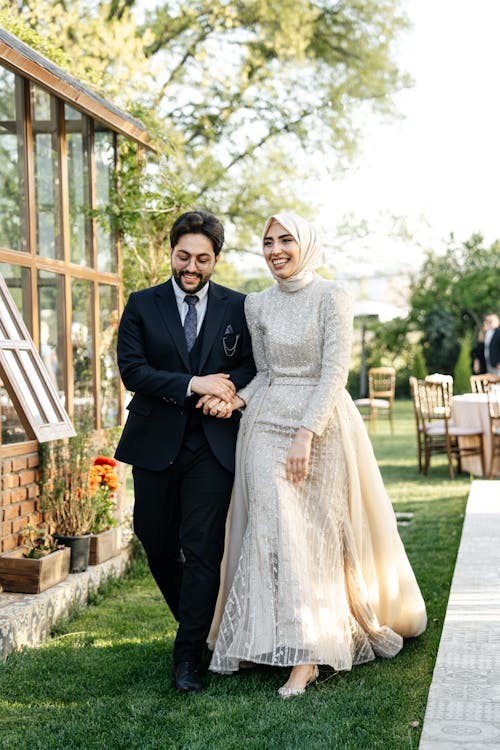 Free Bride and Groom Walking in a Garden and Smiling Stock Photo