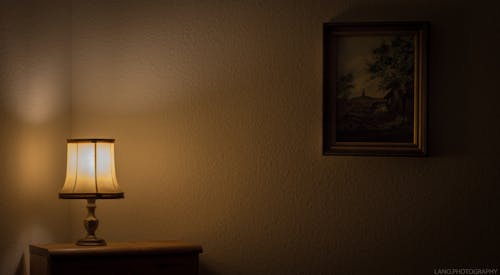 Настольная лампа на тумбочке и картина на стене
