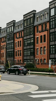 Street view of modern row houses with cars parked along the road, showcasing urban living.