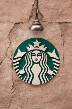 Starbucks emblem on a textured wall under a lamp in Dubai, UAE. 24284274