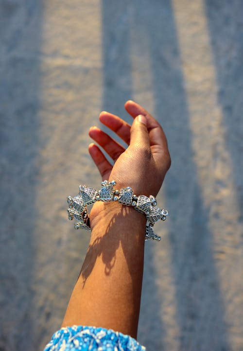 A person holding a bracelet with a silver flower on it