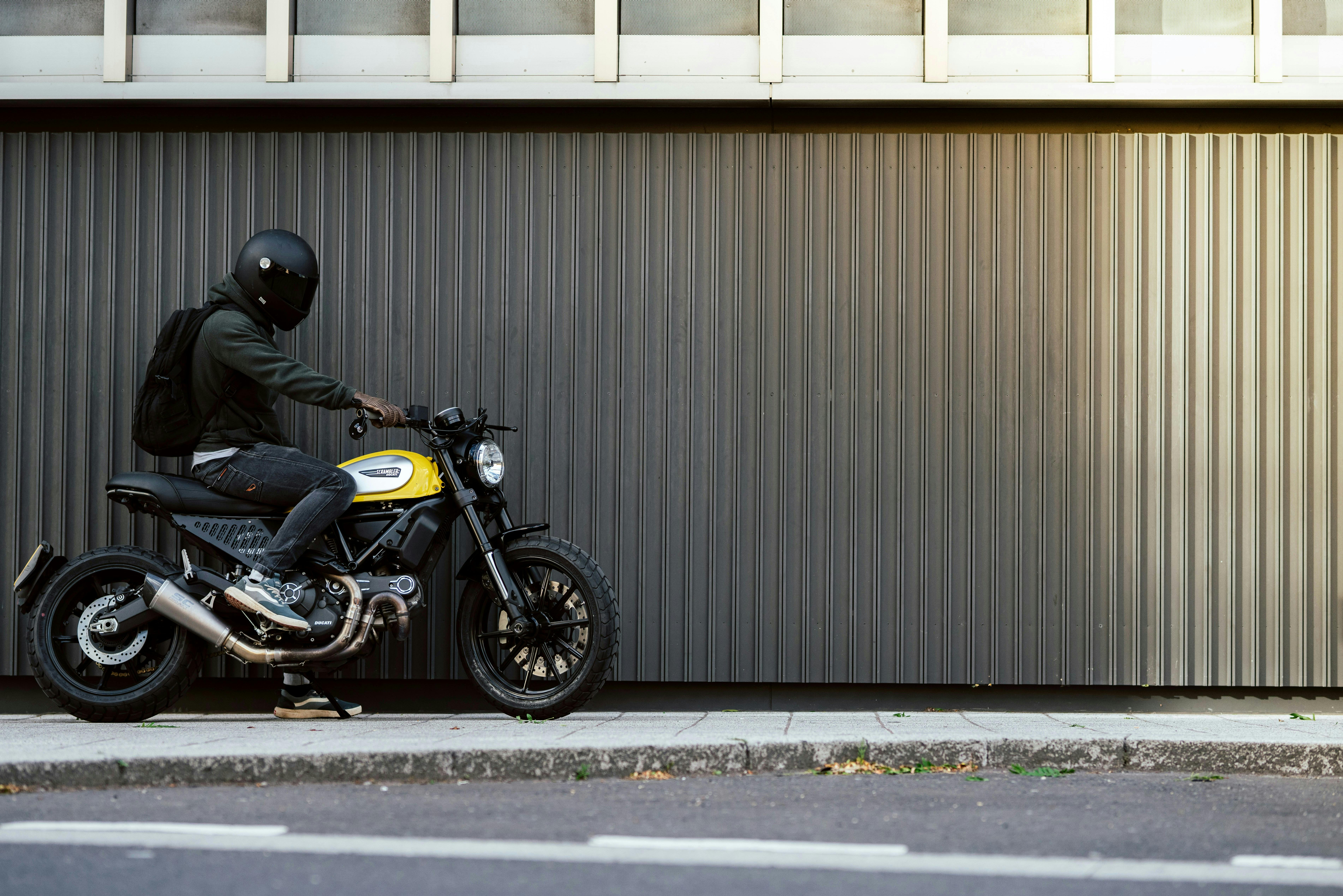 man in helmet on motorbike on sidewalk