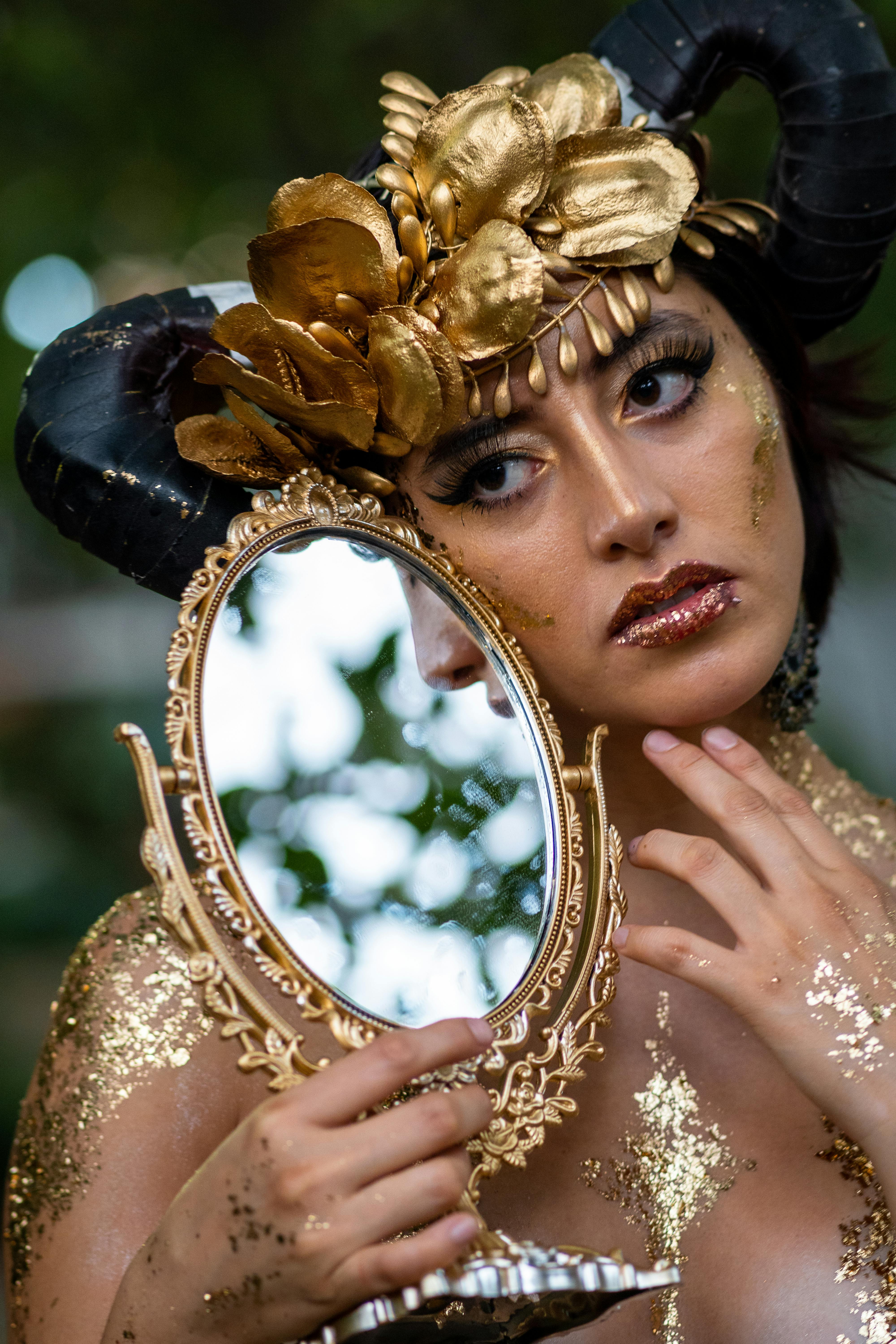 Stunning cosplay portrait featuring a woman in fantasy makeup and costume holding an ornate mirror.