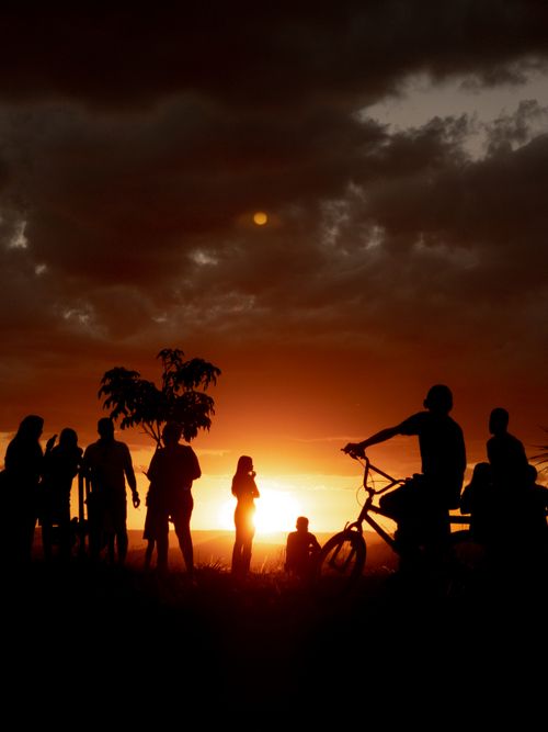 Free Silhouetted people with bikes enjoying a vibrant sunset in Anápolis, Brazil. Stock Photo