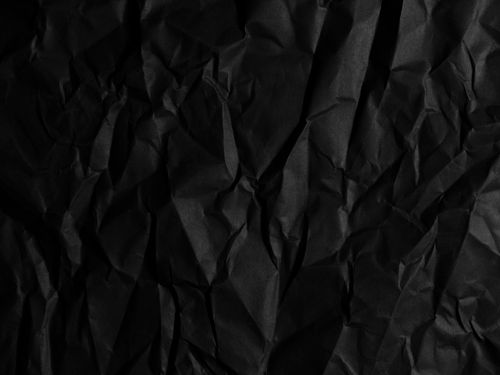 Free Close-up of a black crumpled paper texture, ideal for backgrounds or abstract designs. Stock Photo