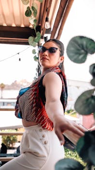 Fashionable woman in sunglasses poses outdoors among greenery in Puebla, Mexico.