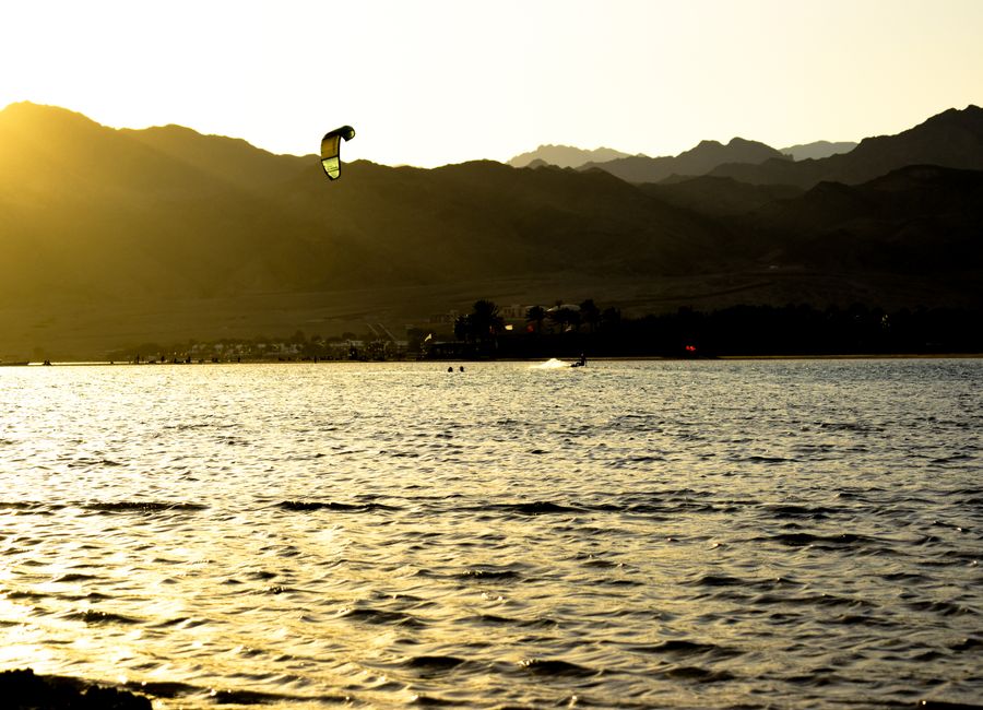 Experience the thrill of kitesurfing during sunset in Dahab, Egypt, with stunning mountain views.