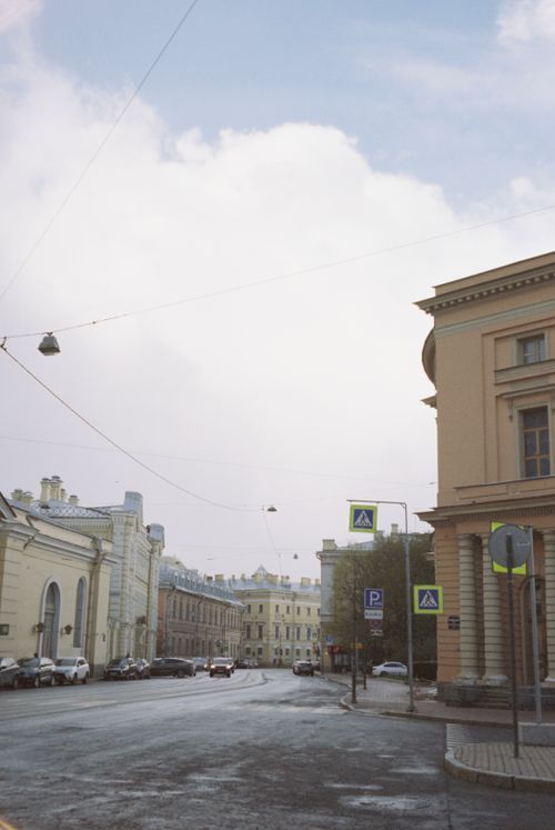 Free A serene city street showcasing classic European architecture with cars parked and overcast sky. Stock Photo