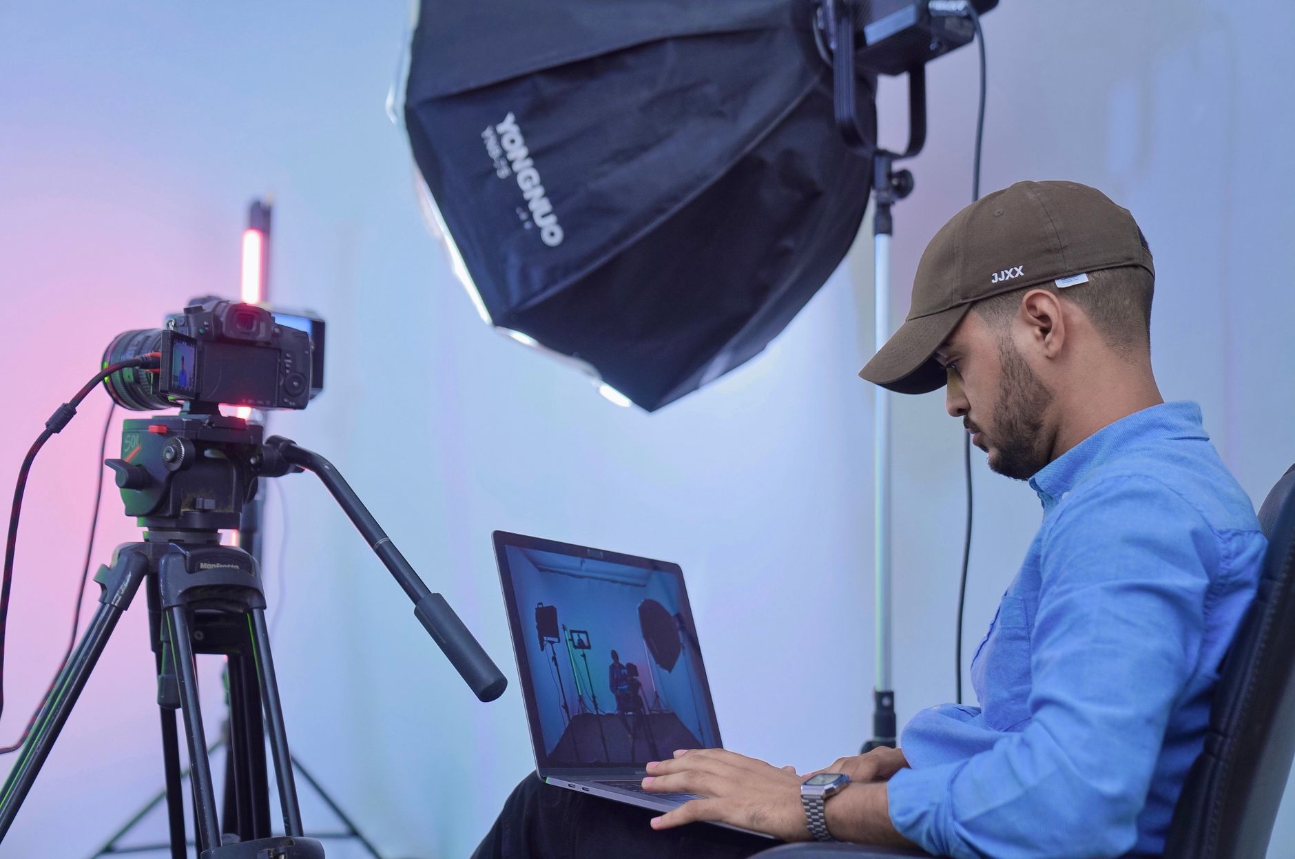 手機人像修圖自然膚色:HSL與選取技巧實戰指南 A photographer works on his laptop in a studio setting, using professional camera equipment and lighting.
