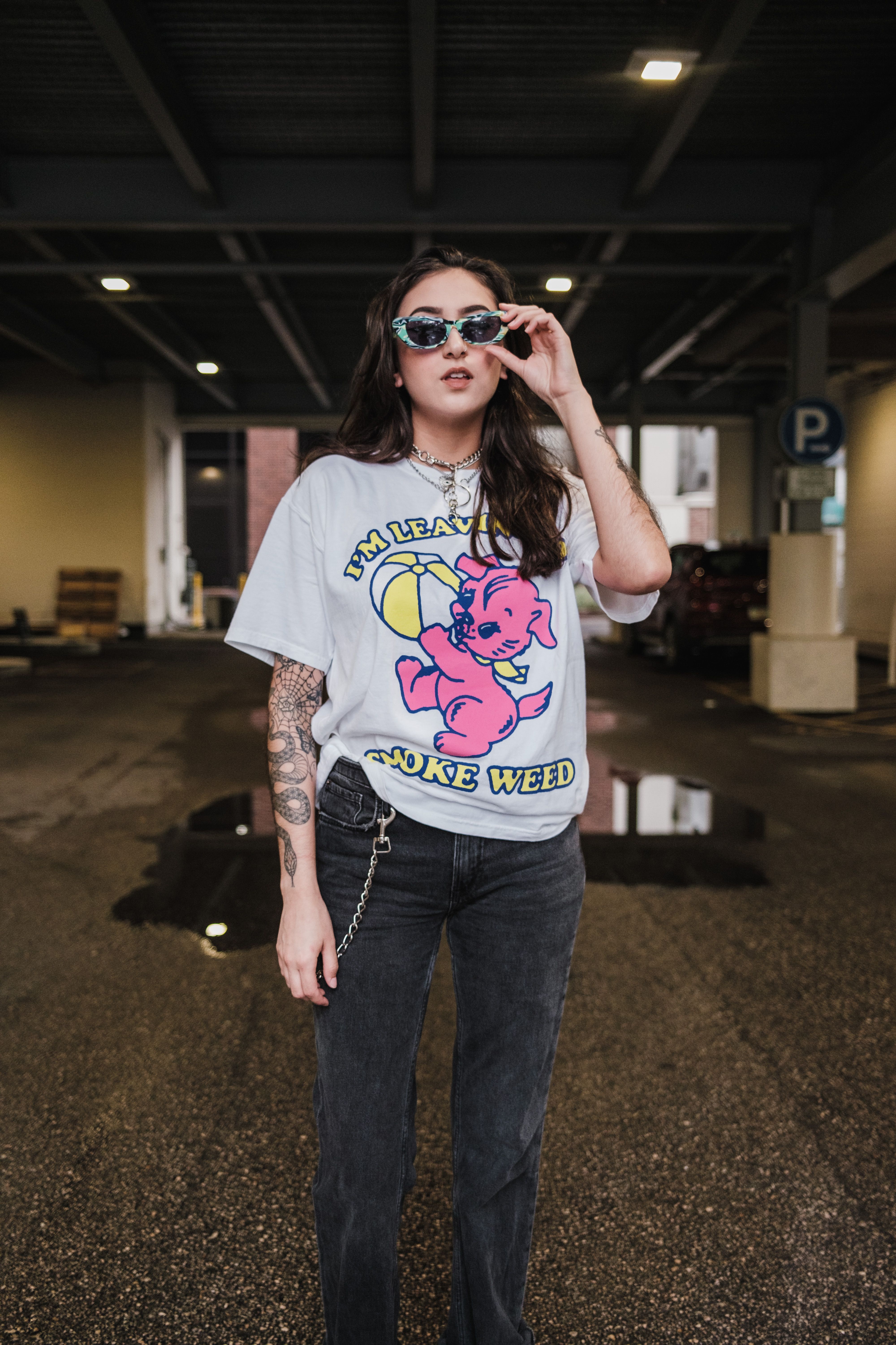 Woman in a graphic T-shirt and dark jeans in an urban parking garage