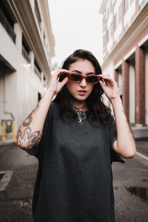 A woman with tattoos wearing sunglasses on the street