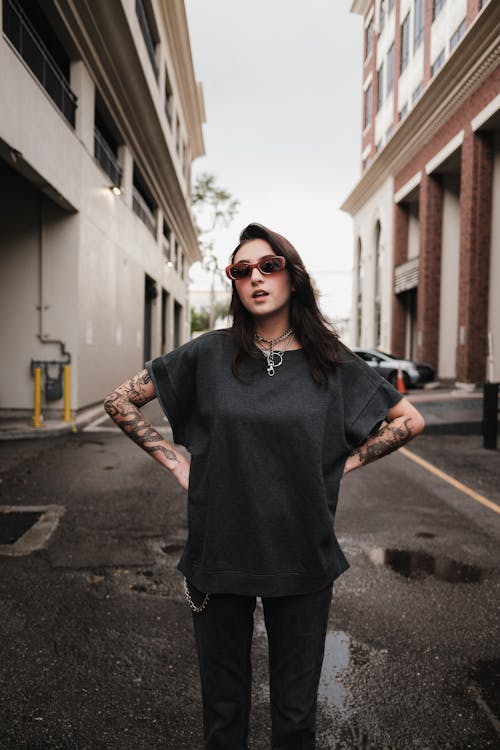 A woman with tattoos standing in the middle of a street