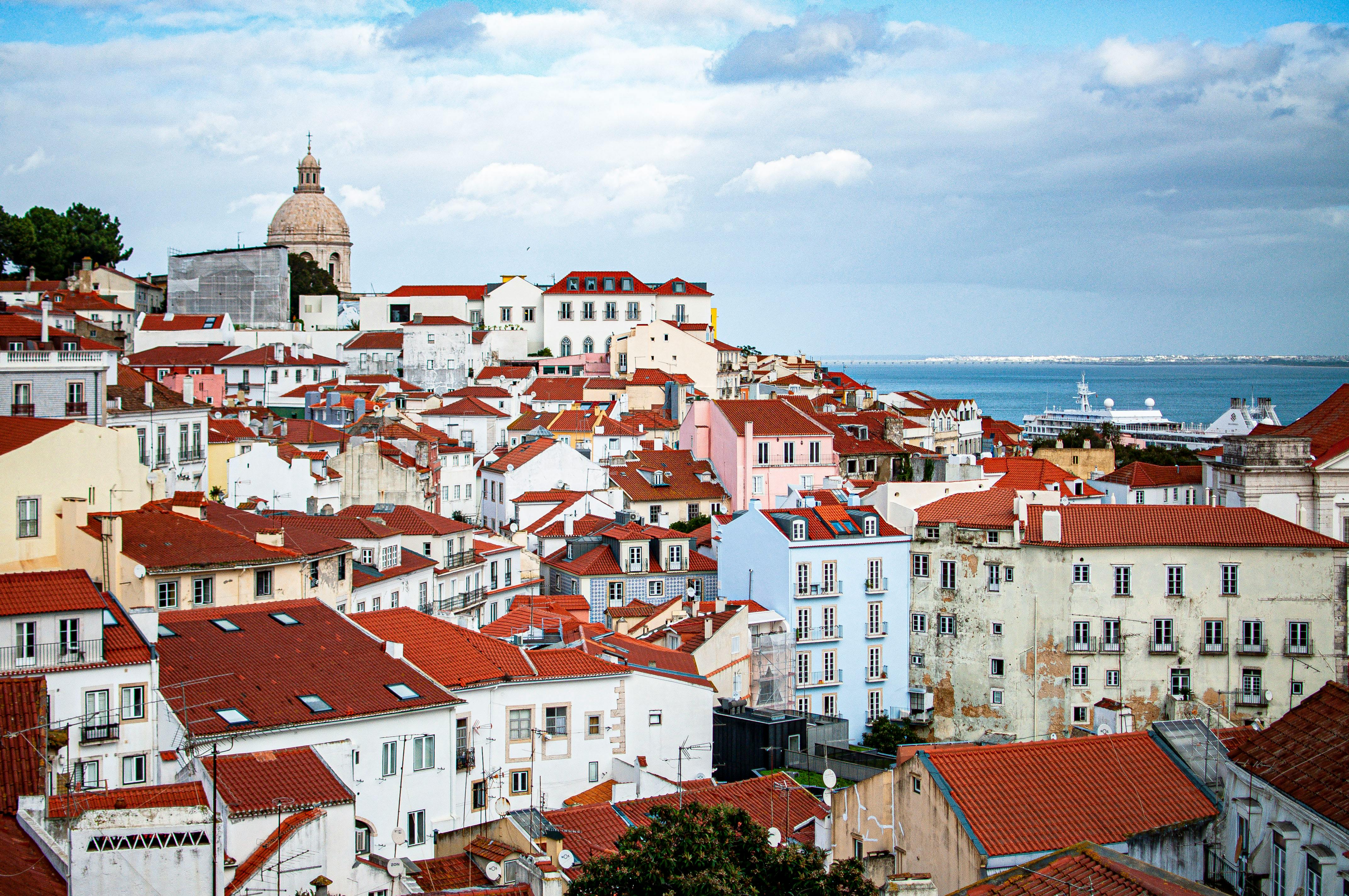 A vibrant view of Lisbon's historic rooftops and the sea, highlighting iconic architecture.