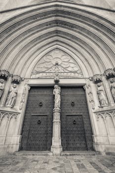 Black and white photo of a gothic cathedral's facade in Tarragona, showcasing intricate architectural details.