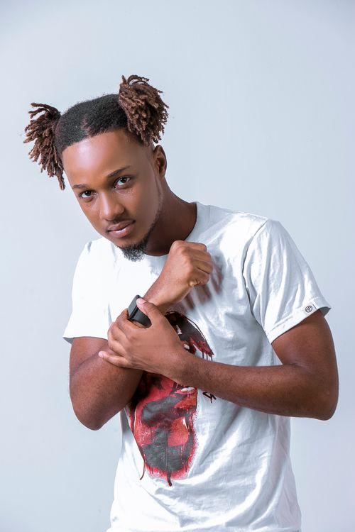 Free Portrait of a stylish young man in a studio with a wristwatch and unique hairstyle, exuding confidence. Stock Photo