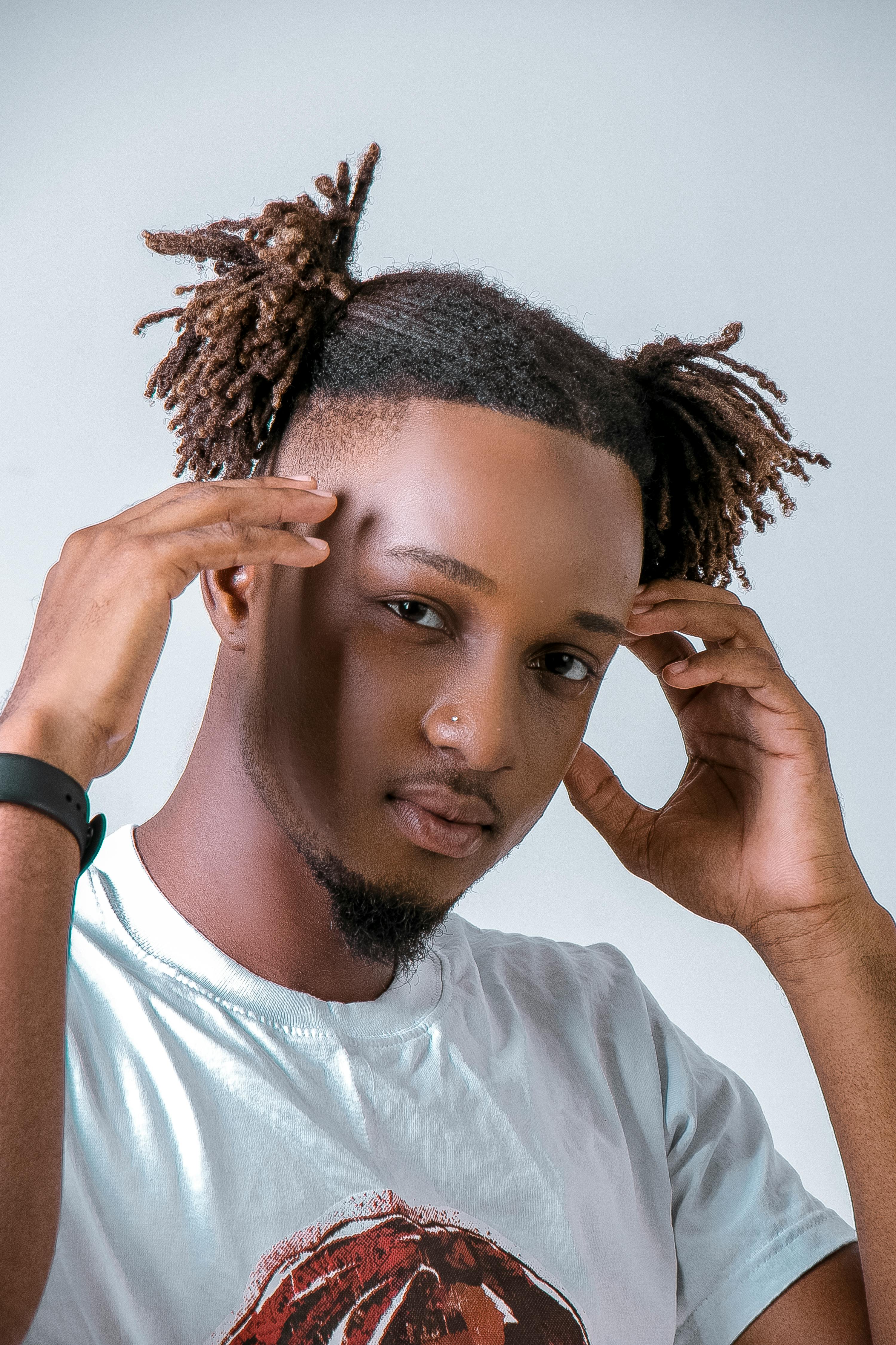 Portrait of a fashionable black man with unique hairstyle in a studio setting.
