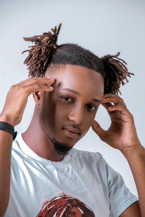 Free Portrait of a fashionable black man with unique hairstyle in a studio setting. Stock Photo