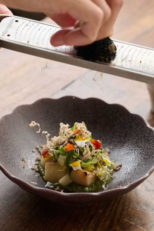 Free A gourmet salad is enhanced with freshly grated toppings by a chef's hand. Stock Photo