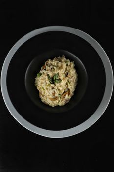 A top-down view of creamy mushroom risotto served in a stylish black bowl.