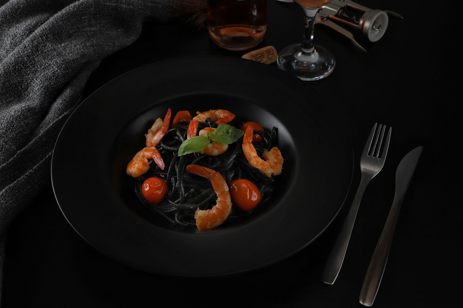 Chitarrine al nero di seppia con gamberi in un piatto nero