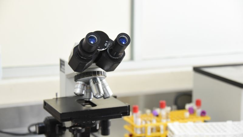 A close-up of a laboratory microscope with test tubes in a scientific research facility.