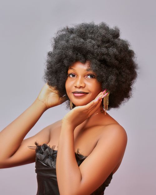 Free Studio portrait of a smiling black woman with afro hair in a stylish pose on a gray background. Stock Photo