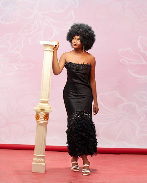 A woman in a black dress posing next to a pillar