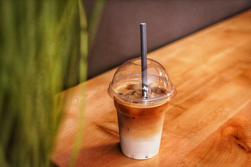 Iced latte in a clear cup on a wooden table — photo by Klárik Loránd on Pexels