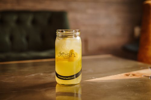 A glass jar filled with lemonade sitting on a table